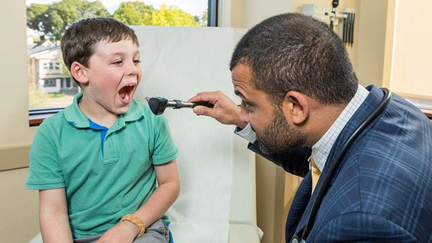 Dr. S. Shahzad Mustafa checking a patient's tonsils